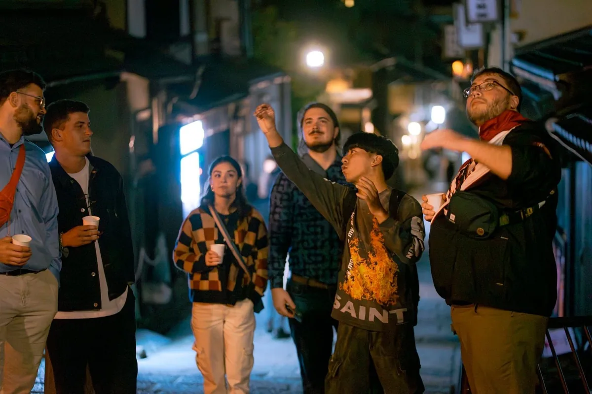 Guests in a night-time alley, looking up where the guide is pointing
