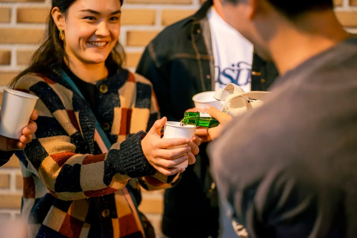 Guests pouring sake into paper cups